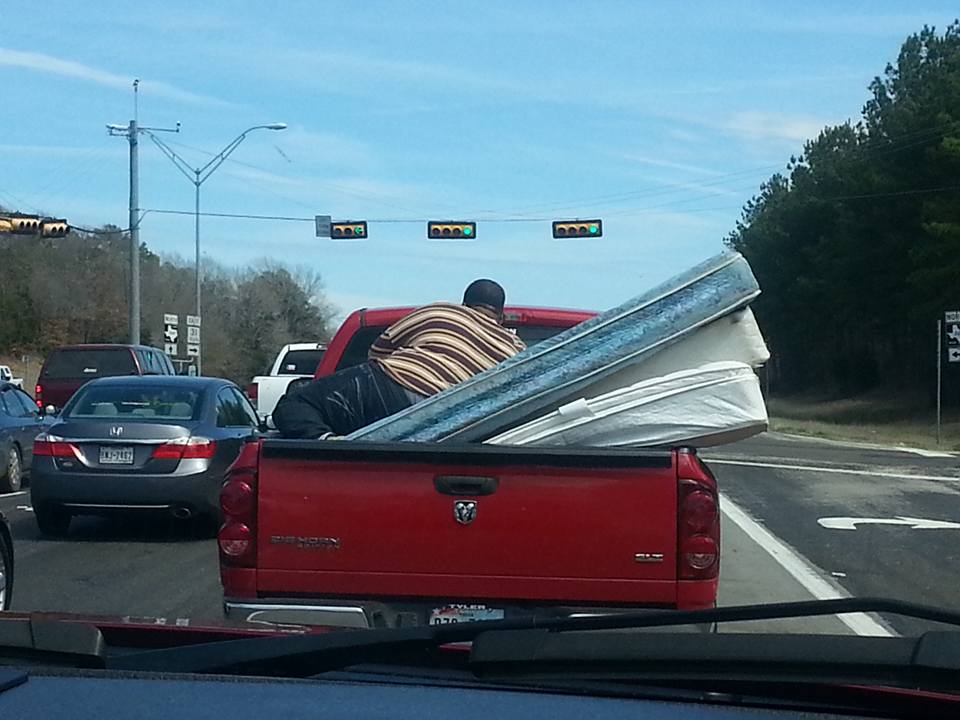 Guy riding on mattresses in truck.jpg